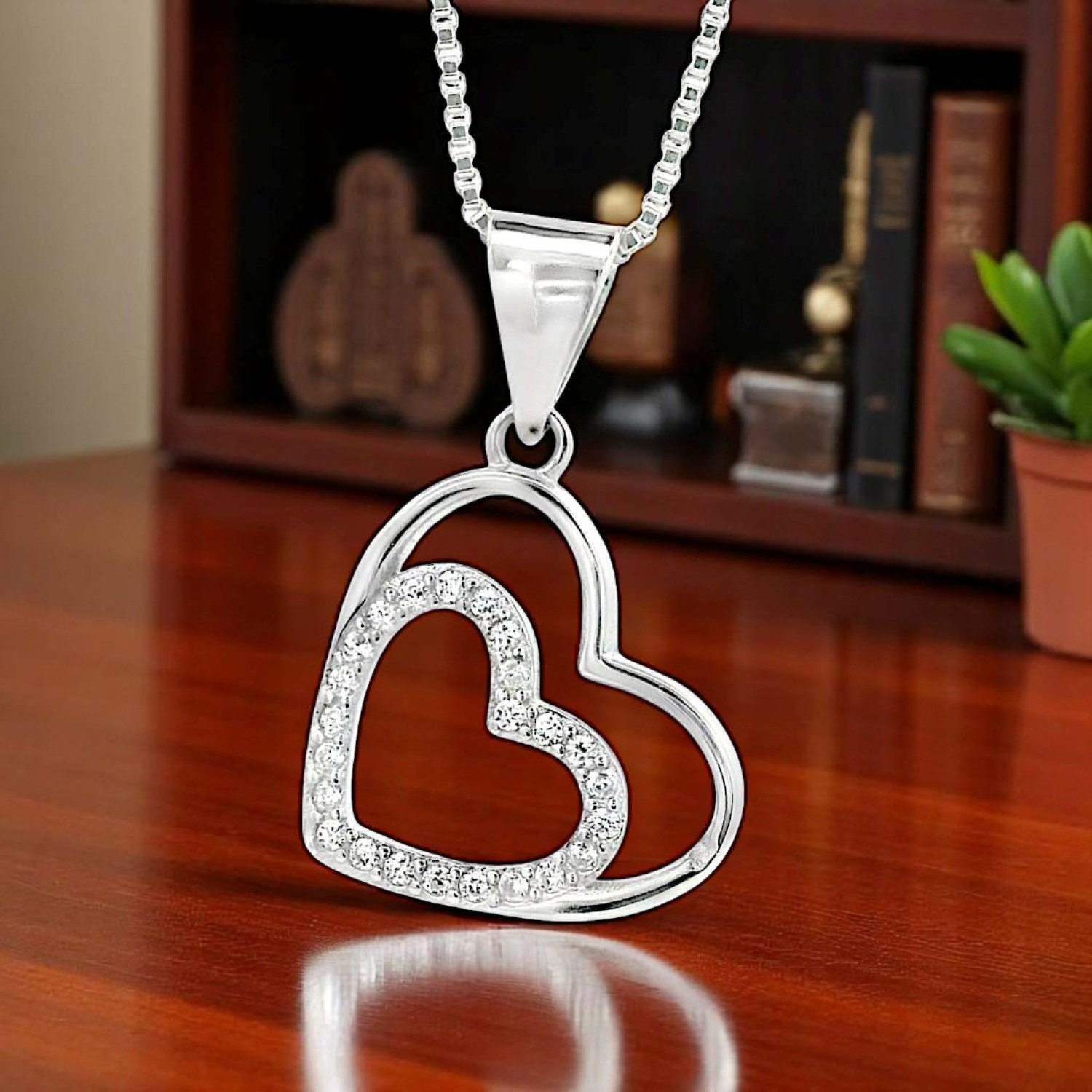 "Elegant Double Heart Pendant Necklace – A Timeless Symbol of Love Elegant Double Heart Pendant Necklace featuring two interlocking hearts—one adorned with shimmering stones and the other with a sleek polished finish. Suspended from a delicate box chain, this timeless jewelry piece symbolizes love and connection.