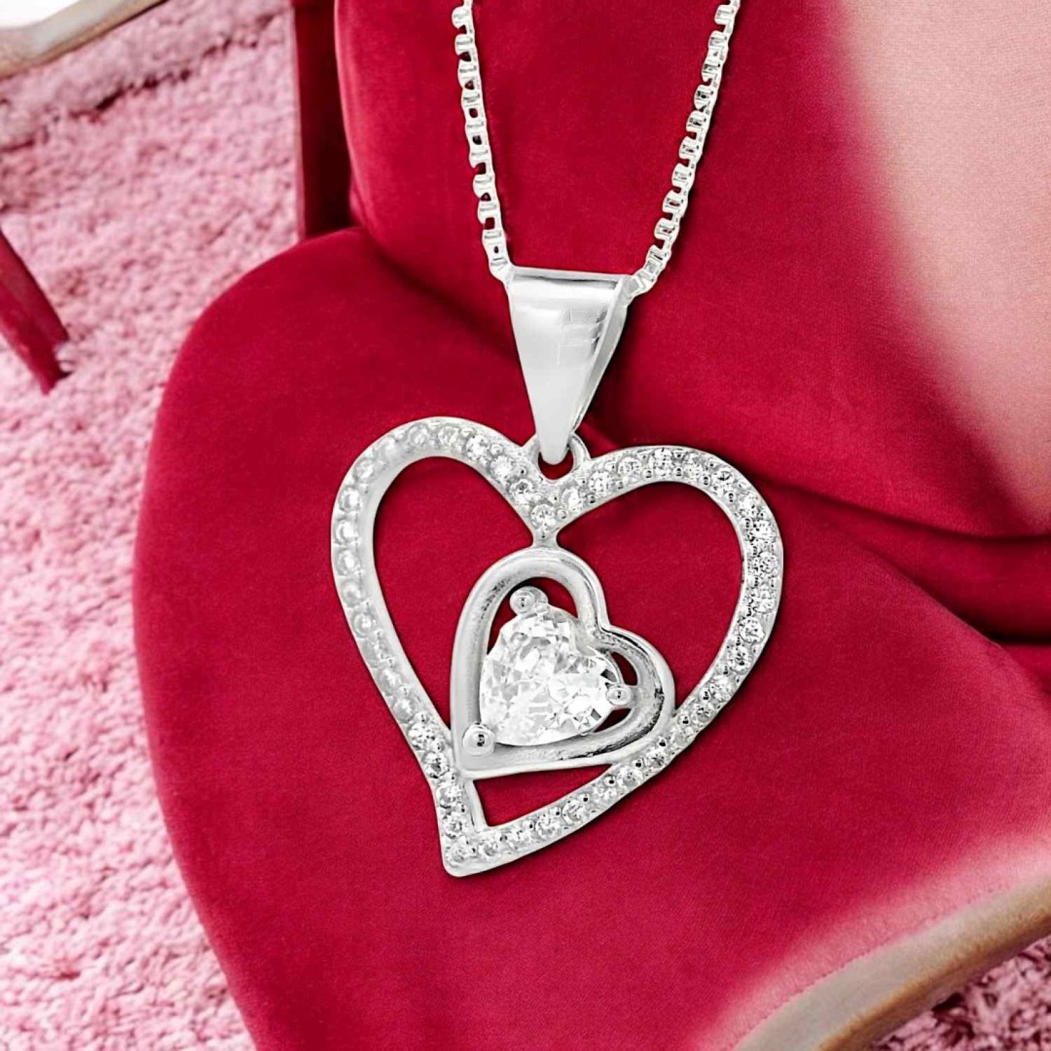 Interlocking Heart Pendant Necklace Interlocking Heart Pendant Necklace | Elegant pendant featuring two interlocking hearts—one adorned with sparkling stones and the other holding a central heart-shaped gemstone, symbolizing love and connection.