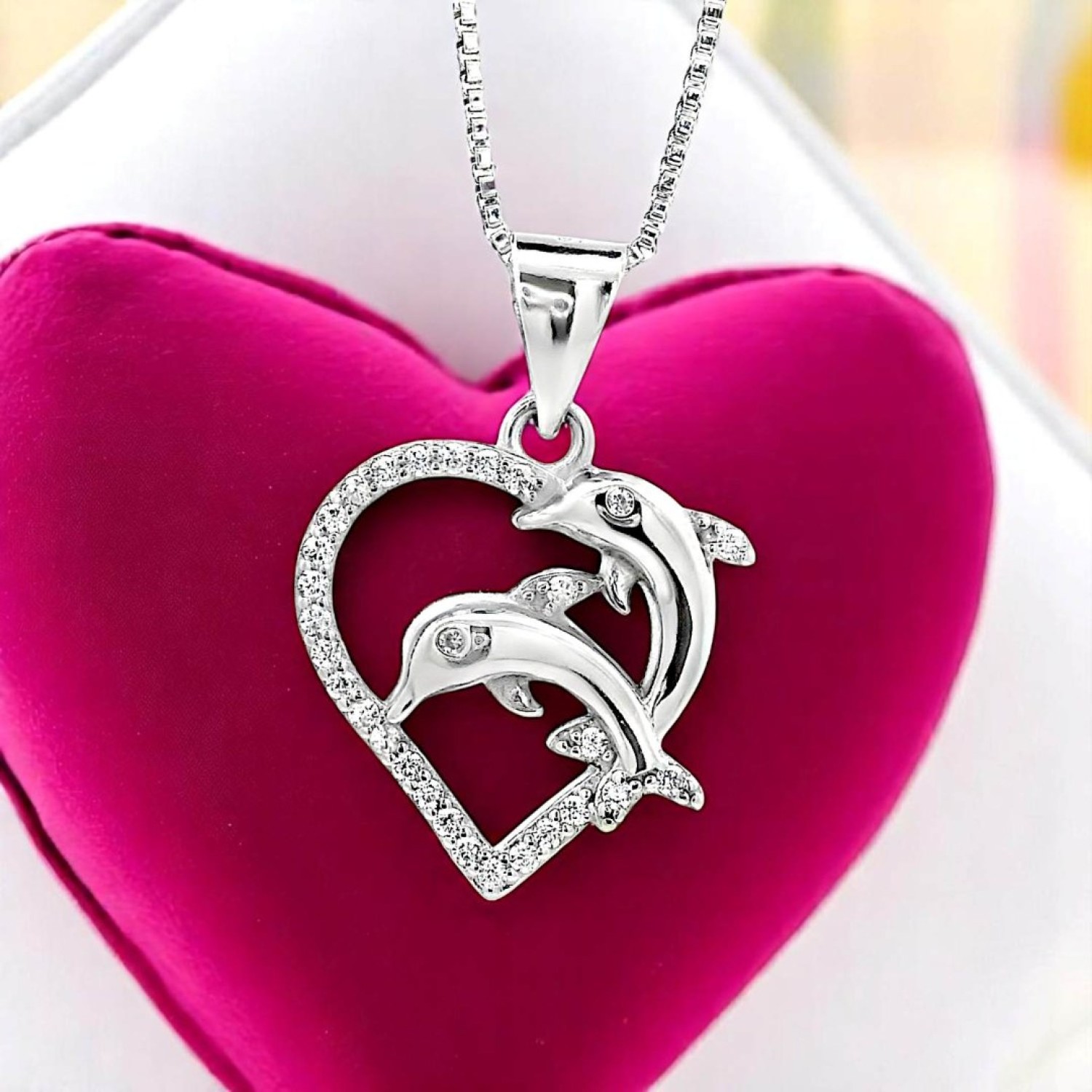 Dolphin Heart Pendant – Christies Jewellery NZ- Christies Jewellery Online and Auckland Dolphin Heart Pendant by Christies Jewellery NZ | A silver heart-shaped pendant featuring two intertwined dolphins, accented with small sparkling stones, hanging from a delicate chain.