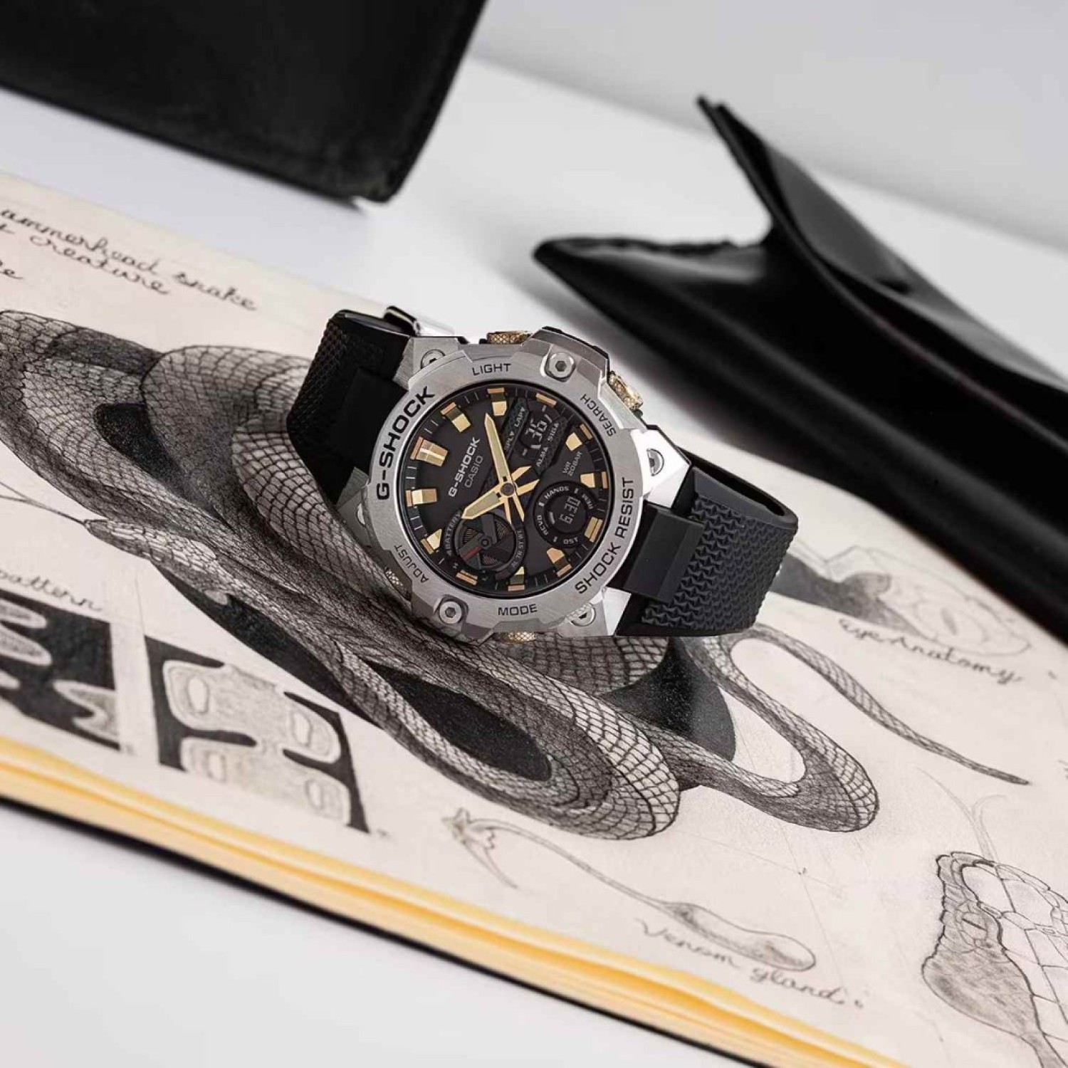 "GSTB400CX-1A Casio G-Shock G-STEEL Watch – Year of the Snake Special Edition GSTB400CX-1A Casio G-Shock G-STEEL Watch with a silver metal bezel, black dial, gold accents, and snake-pattern details inspired by the Year of the Snake. Features shock resistance, solar power, Bluetooth connectivity, and a durable resin band.