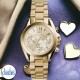 MK5798 Michael Kors Womens Chronograph Bradshaw Watch. From the Bradshaw Mini range this model is made from IP gold plated steel and has a round case shape. It has a champagne colour dial with combination hour markers in gold, slender gold hands, chronogr