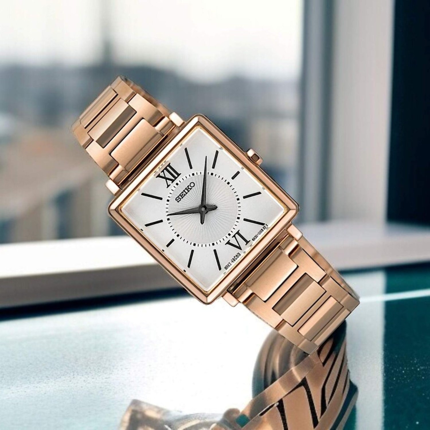 SWR112P Seiko Ladies Analogue Square Watch – Rose gold-tone stainless steel case, white dial with Roman numerals, and a sleek stainless-steel bracelet for timeless elegance.