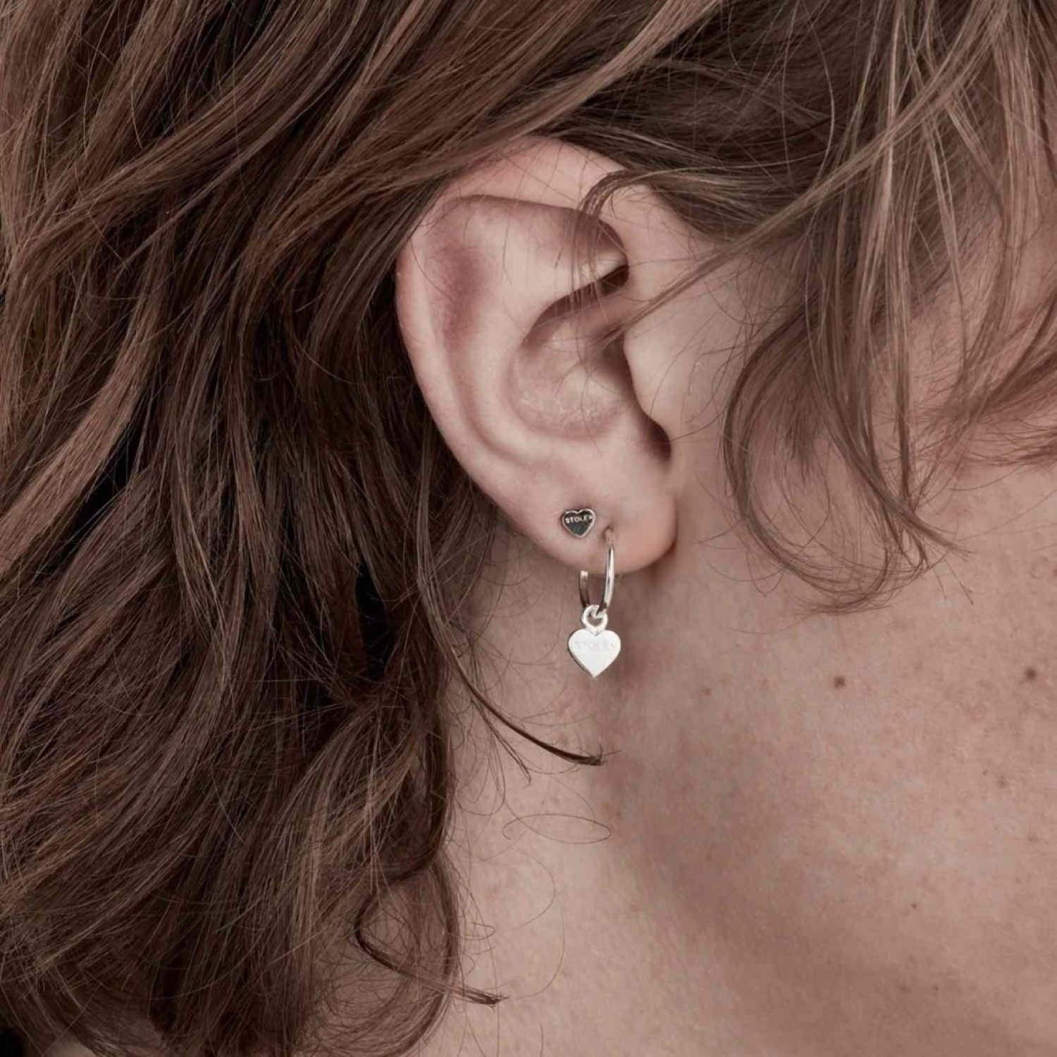 Tiny Stolen Heart Earrings – Stolen Girlfriends Club Jewellery Tiny Stolen Heart Earrings by Stolen Girlfriends Club Jewellery | A pair of heart-shaped stud earrings with the word 'STOLEN' engraved on the front of each heart.