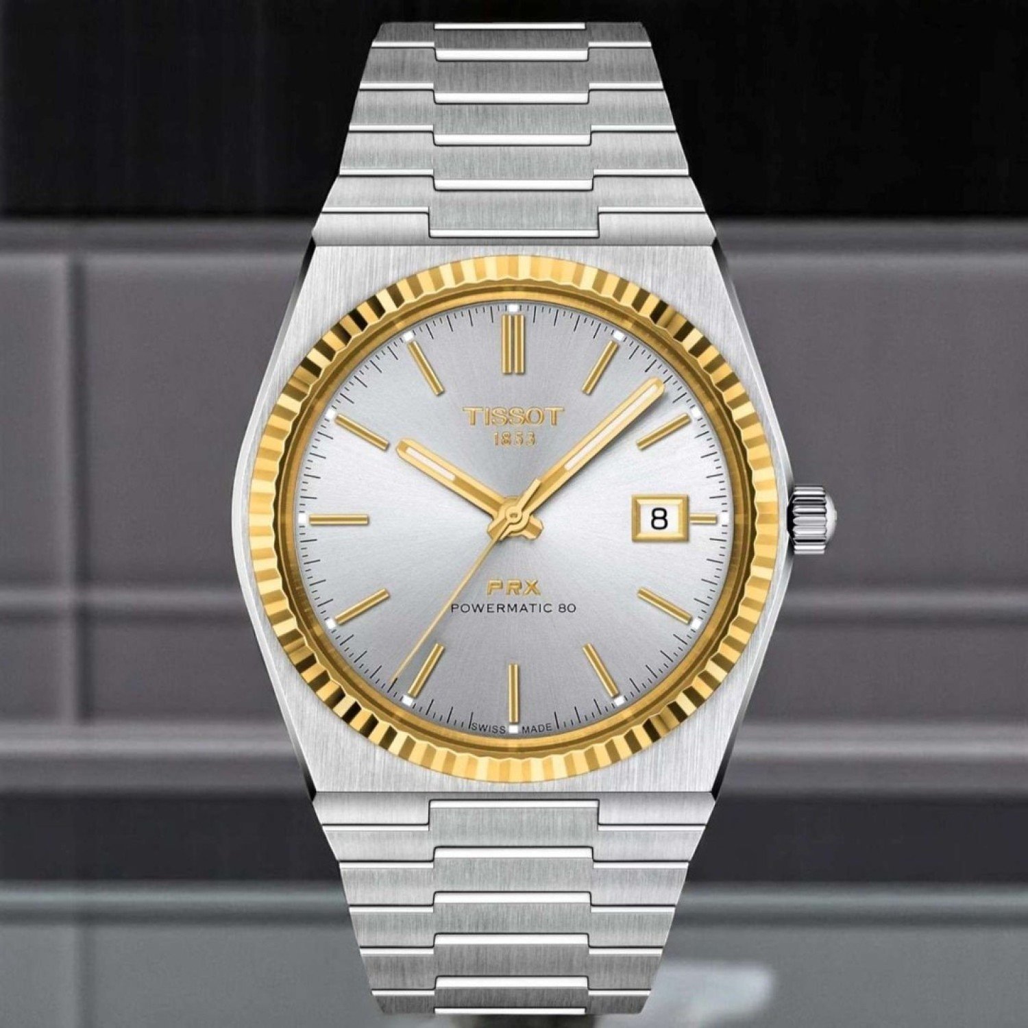 Tissot PRX Powermatic 80 18K Gold Bezel 40mm T9314074103101 by Tissot Watches NZ | TISSOT PRX Powermatic 80 wristwatch featuring a stainless steel bracelet, a silver dial, and a yellow gold bezel. Includes sleek hour markers, gold hands, and a date window